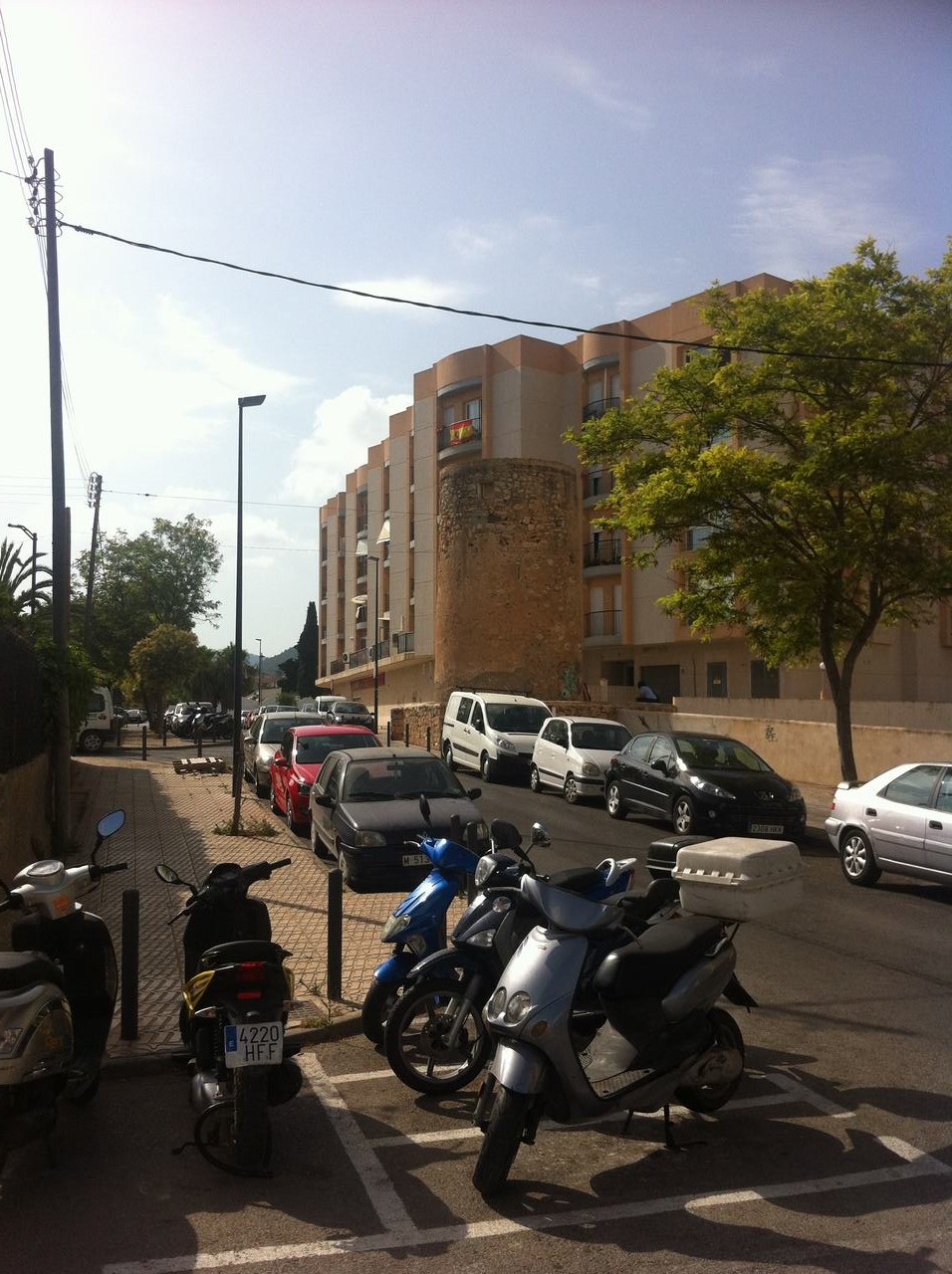 Ulice s auty a skútry, bytový dům s kamennou věží, SPZ 4220 HFF.