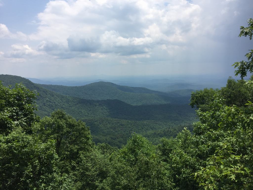 Výhled na zalesněné horské hřebeny v dálce pod zataženou oblohou
