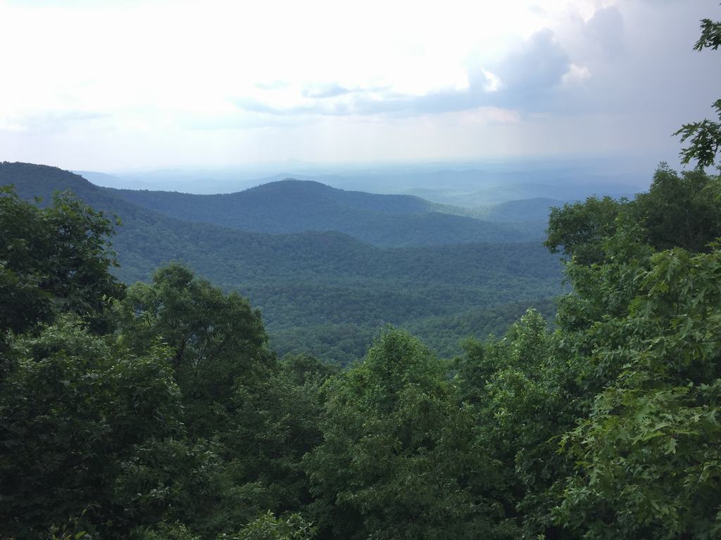 Výhled na zalesněné horské hřebeny a údolí pod zataženou oblohou
