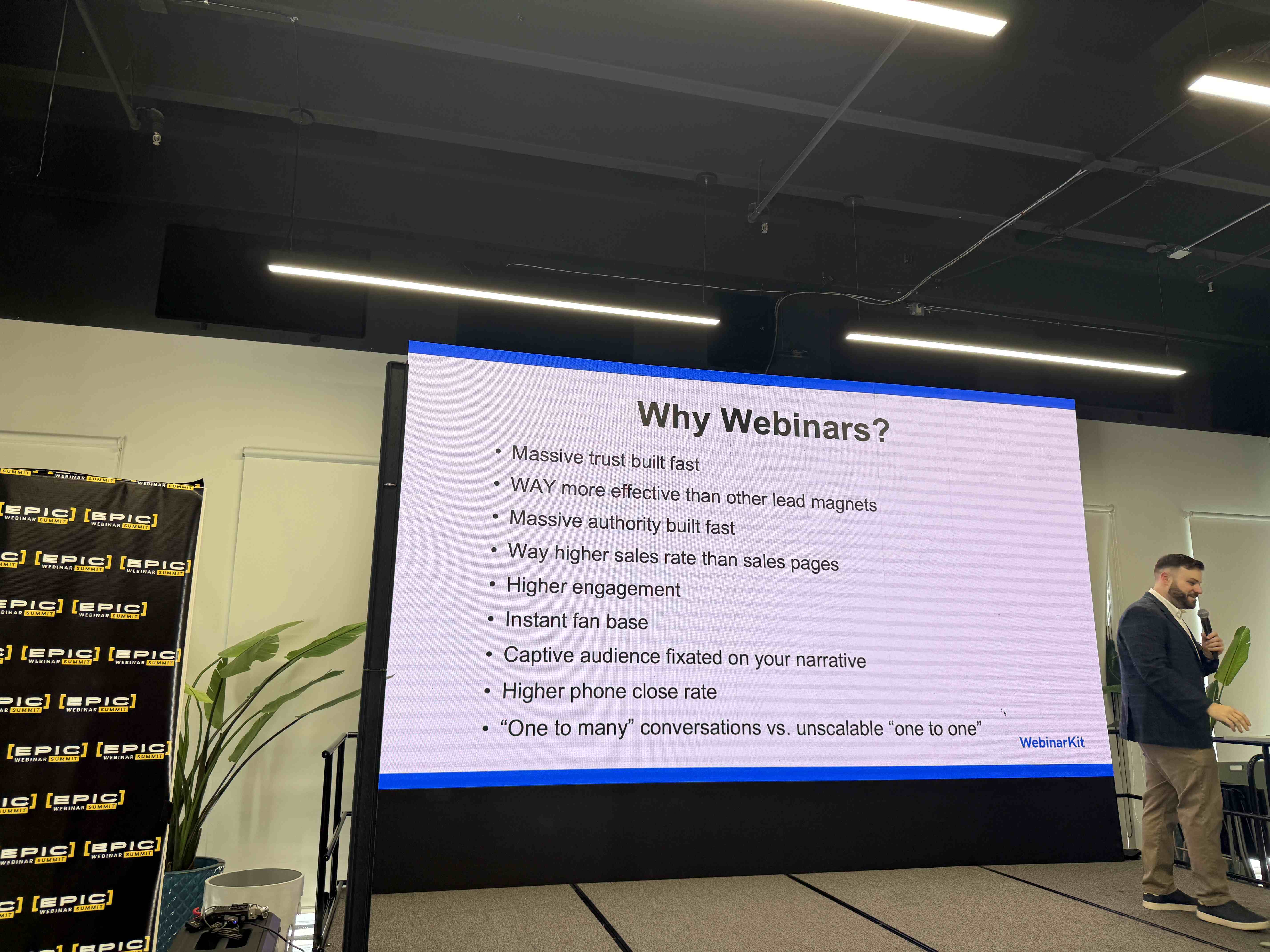 Prezentace se slidem Why Webinars? a řečník s mikrofonem na pódiu