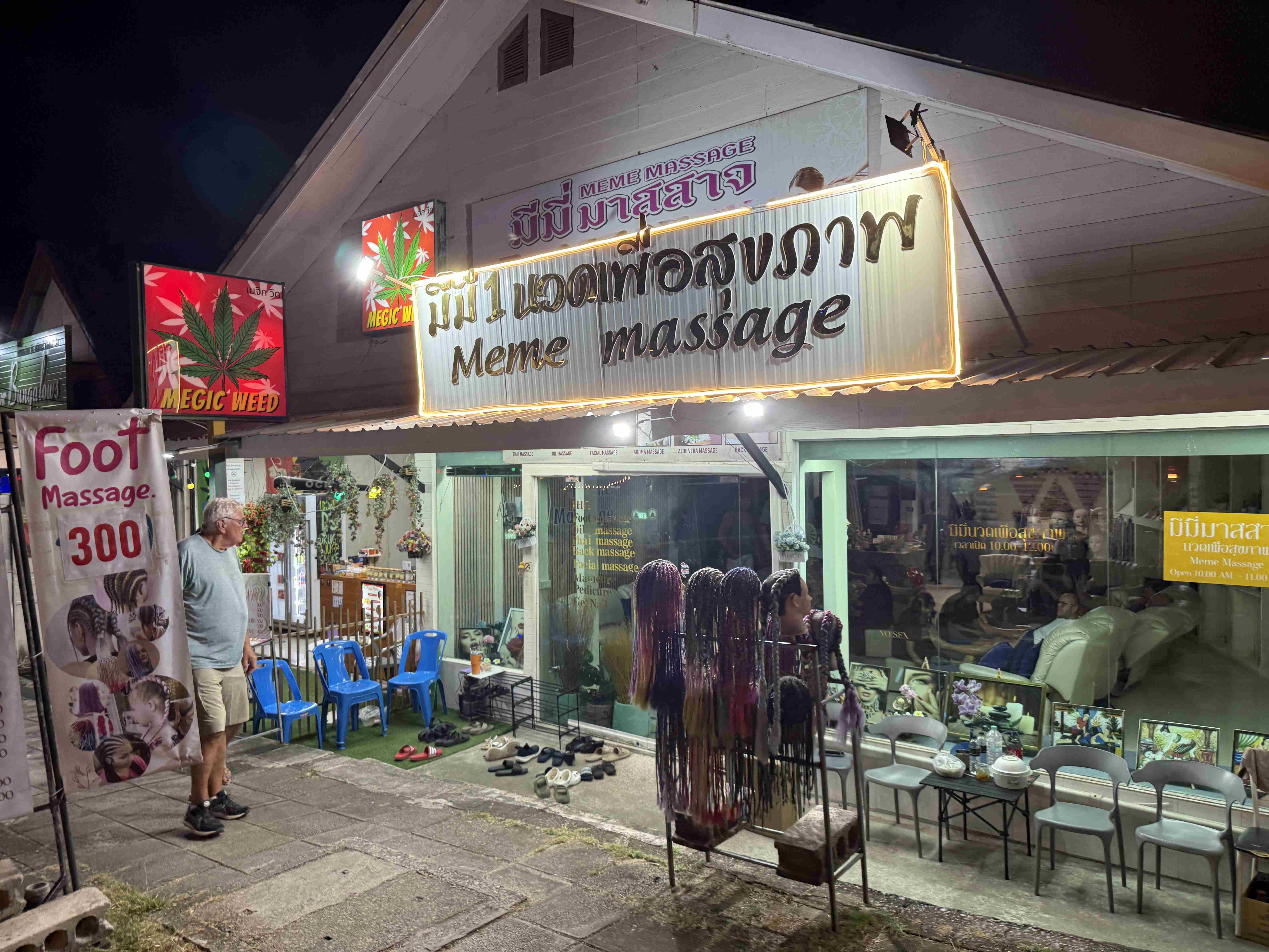 Noční ulice, salon Meme massage, cedule Foot Massage 300 a Magic Weed.
