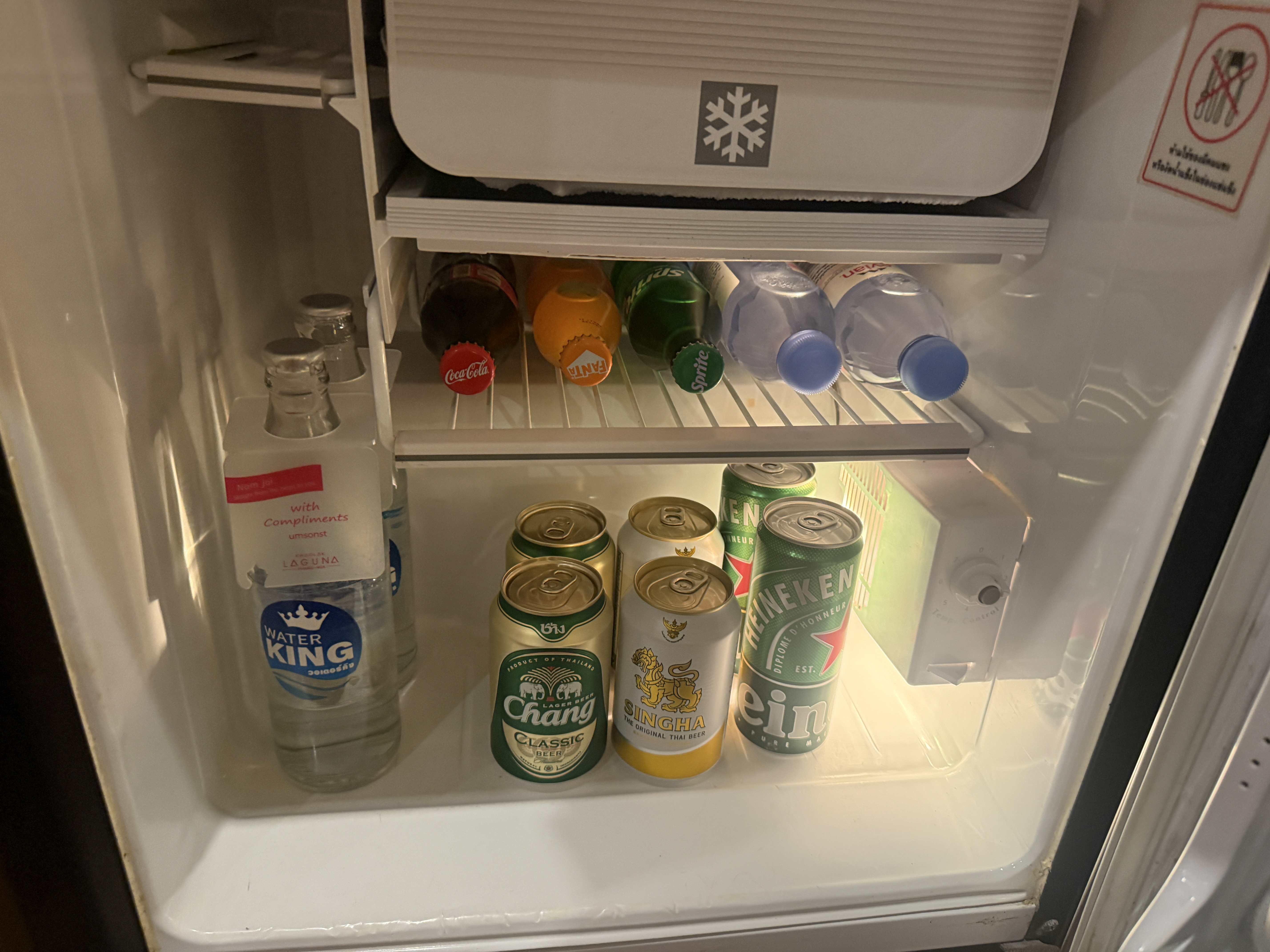 Otevřený minibar: with compliments; Water King, Coca‑Cola, Fanta, Sprite, piva Chang, Singha, Heineken.