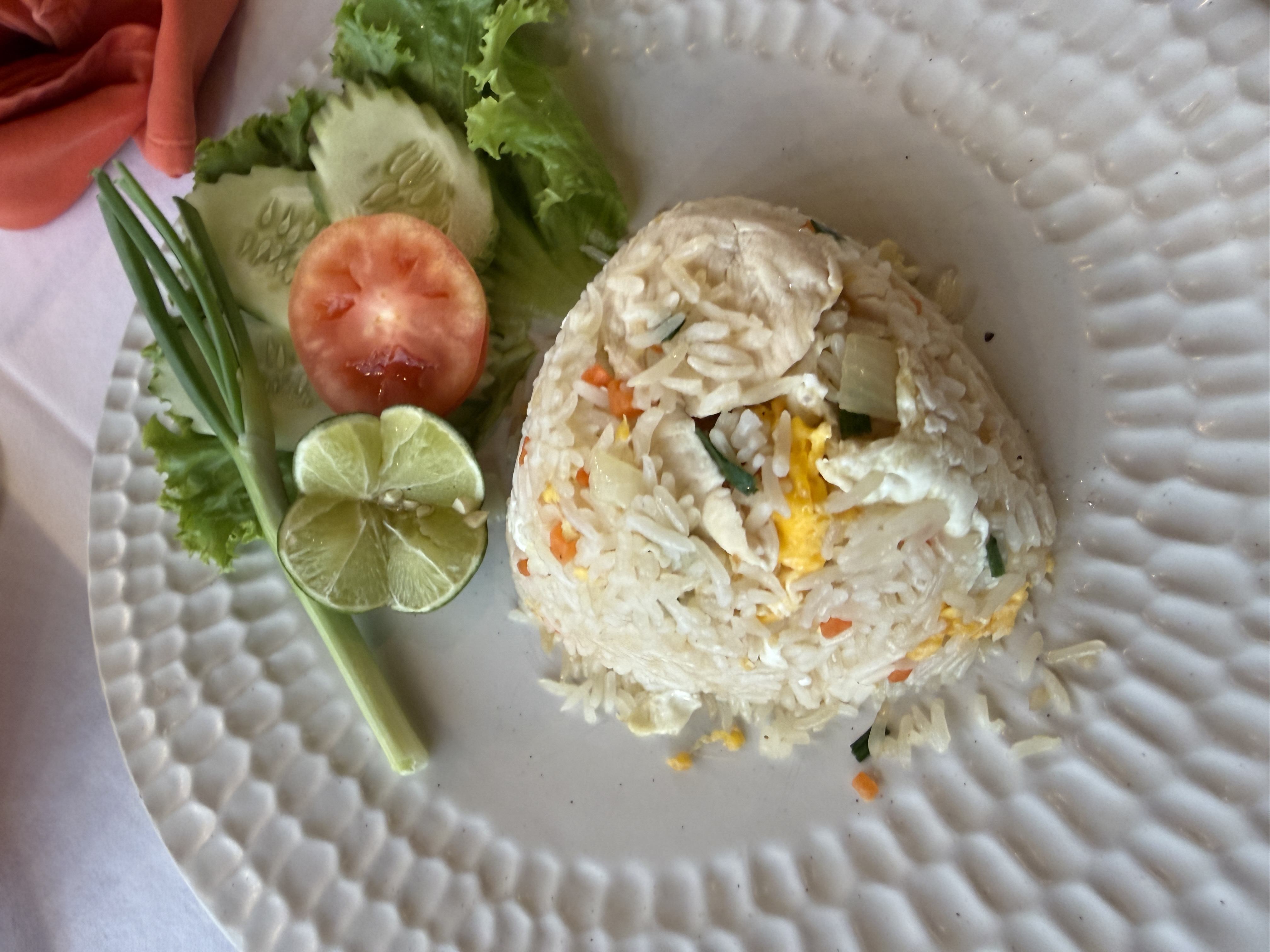 Porce thajské smažené rýže s vejcem a kuřetem, limetka a zelenina na talíři