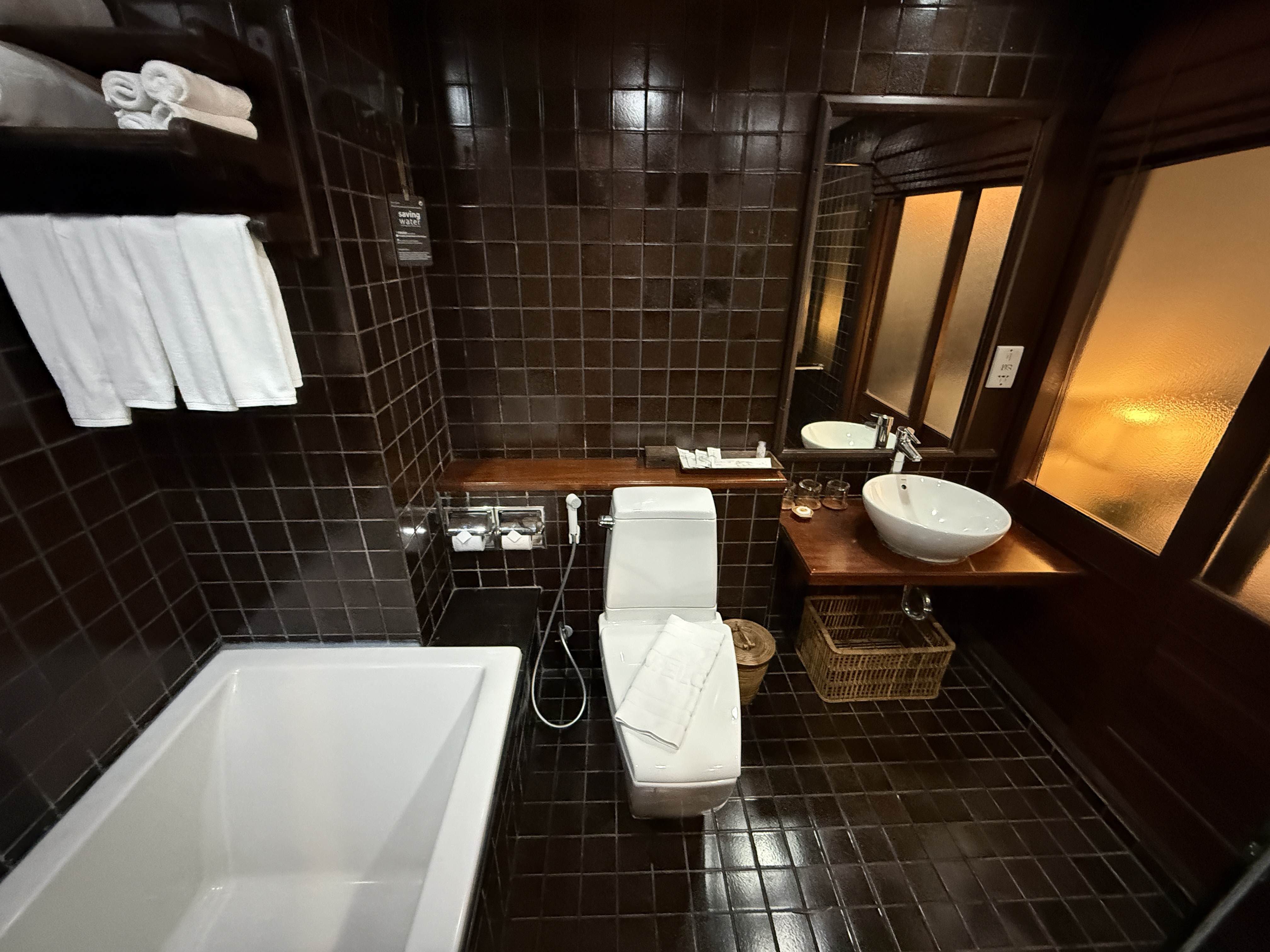 Hotelová koupelna s vanou, WC, umyvadlem a cedulkou Saving water