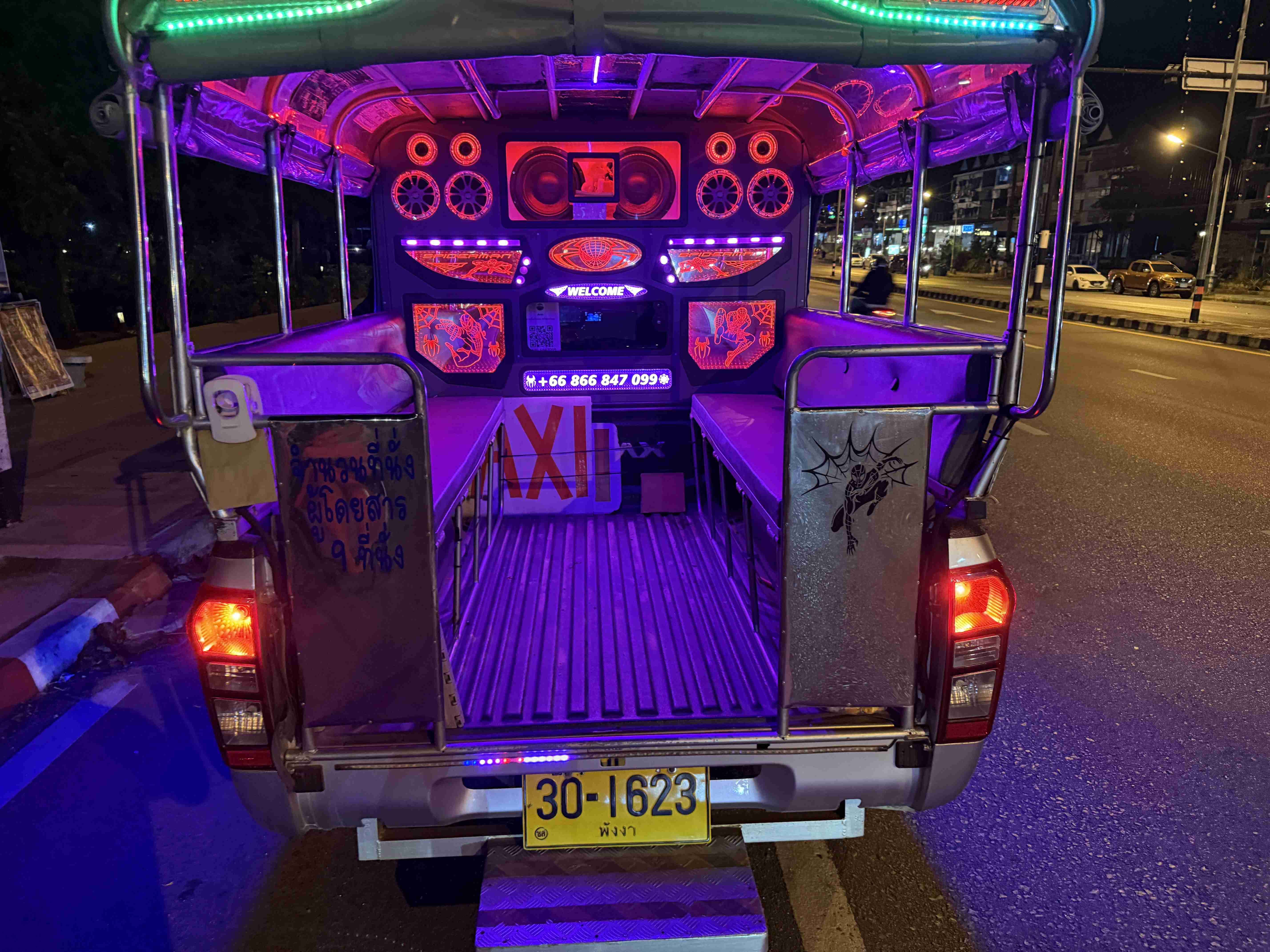 Osvětlený interiér thajského taxi pick-upu se zvukovou aparaturou, nápisy TAXI a WELCOME.