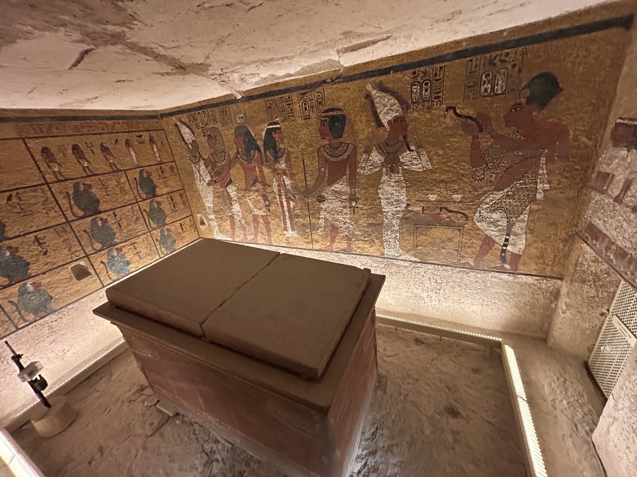 Mumie v kamenné komoře s barevnými egyptskými malbami na stěnách