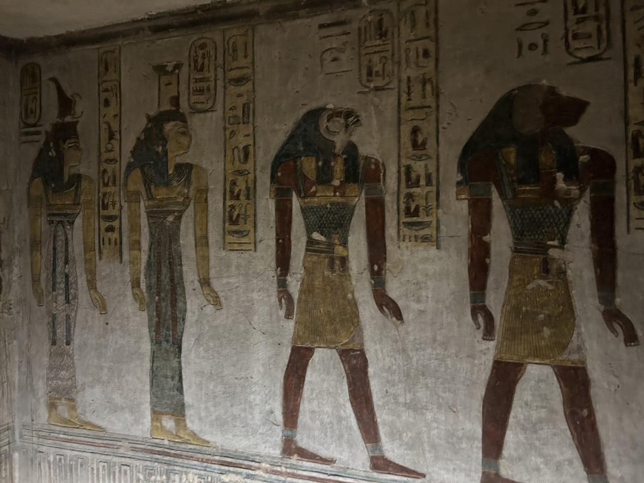 Barevná malba egyptských postav a hieroglyfů na stěně hrobky