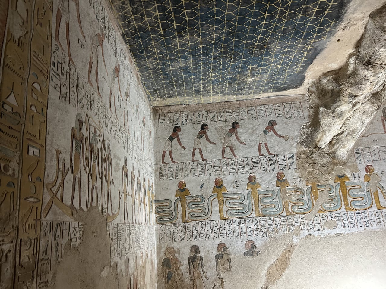Malovaná egyptská hrobka s hieroglyfy a postavami na stěnách a stropě