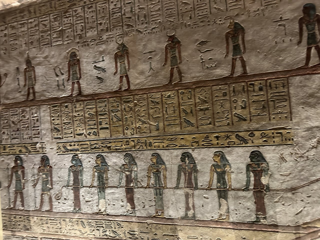 Barevná egyptská nástěnná malba s hieroglyfy a postavami v řadách