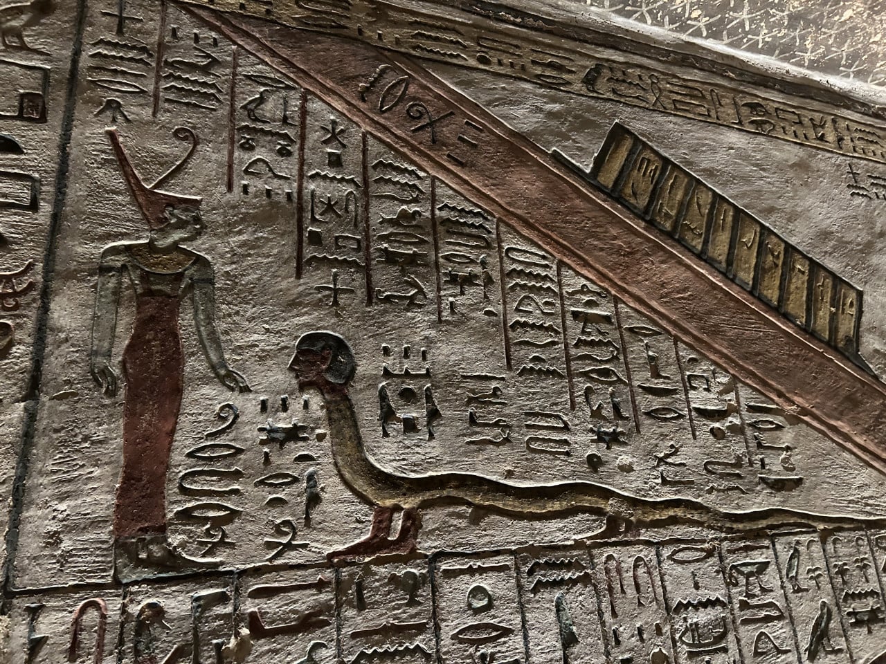 Barevná reliéfní egyptská hieroglyfická stěna s postavou ptáka a lidské postavy