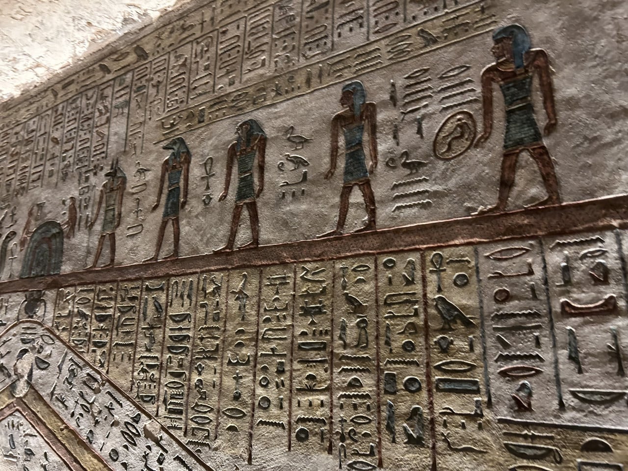 Barevná egyptská hieroglyfická výzdoba na stěně hrobky v Údolí králů