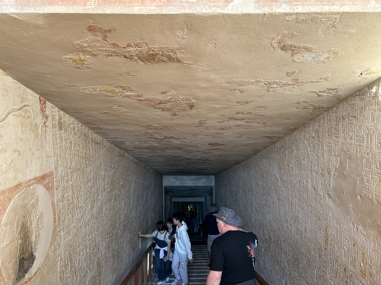 Návštěvníci procházejí zdobenou chodbou hrobky s egyptskými hieroglyfy.