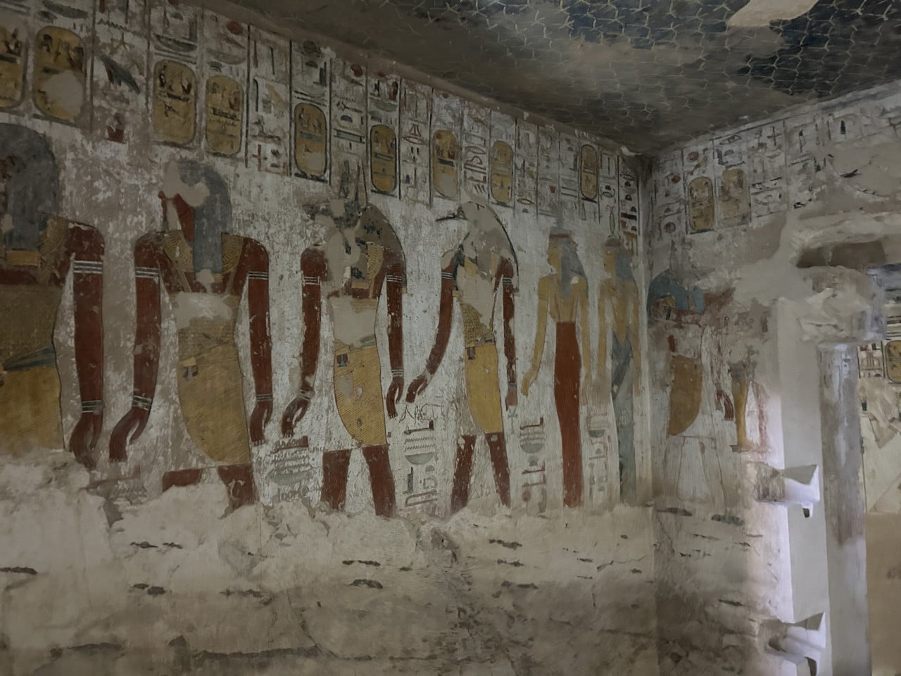 Malovaná hrobková stěna s egyptskými postavami a hieroglyfy v Údolí králů