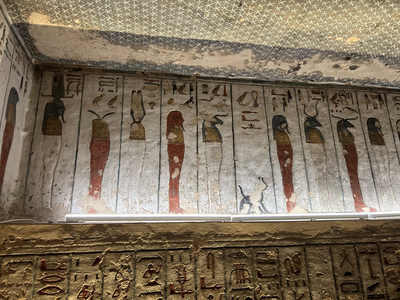 Barevné egyptské hieroglyfy a malby na stěně hrobky v Údolí králů
