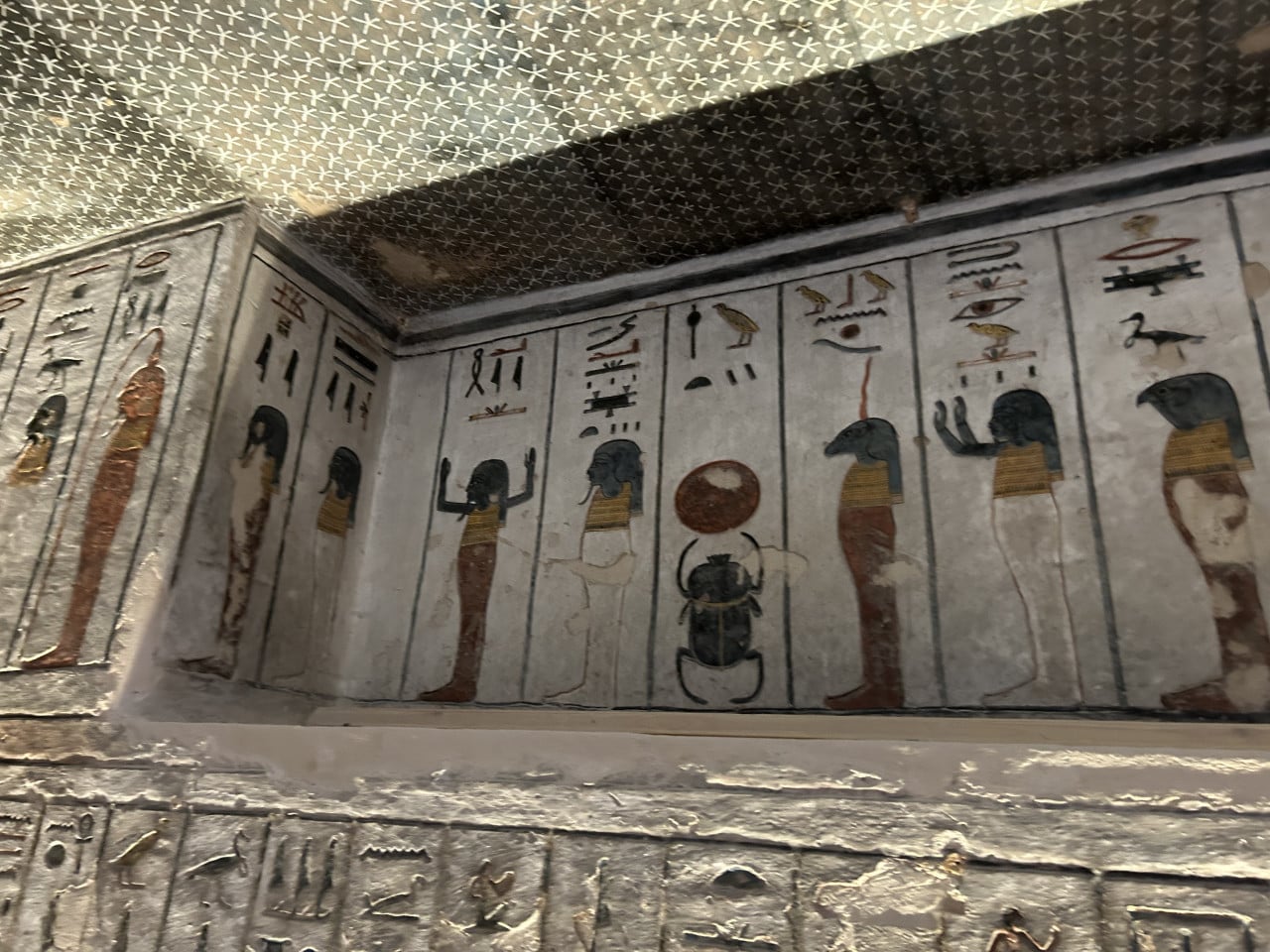 Barevná výmalba stěn hrobky s egyptskými hieroglyfy a božstvy artefakty.