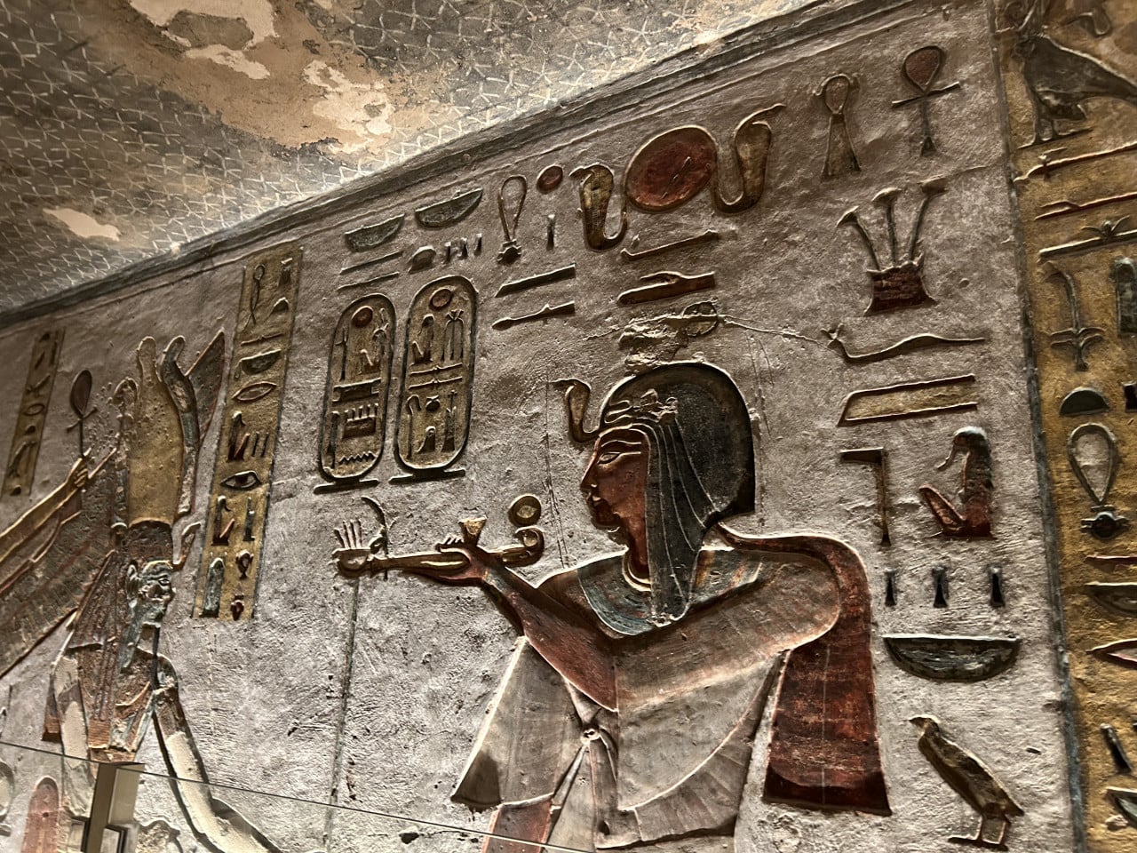 Barevné egyptské reliéfy a hieroglyfy na stěně hrobky v Údolí králů