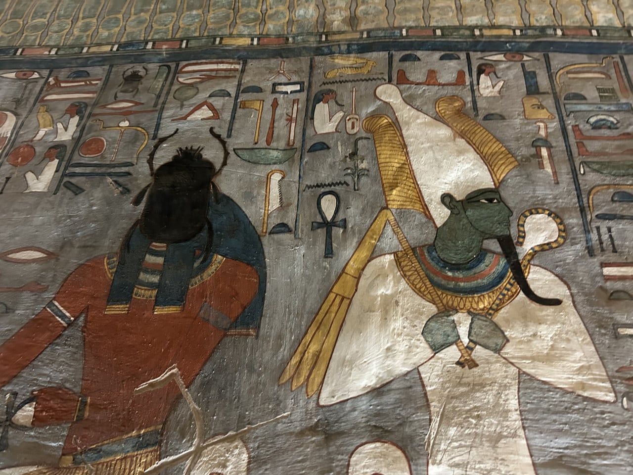 Barevná egyptská nástěnná malba s bohy a hieroglyfy na stěně hrobky.