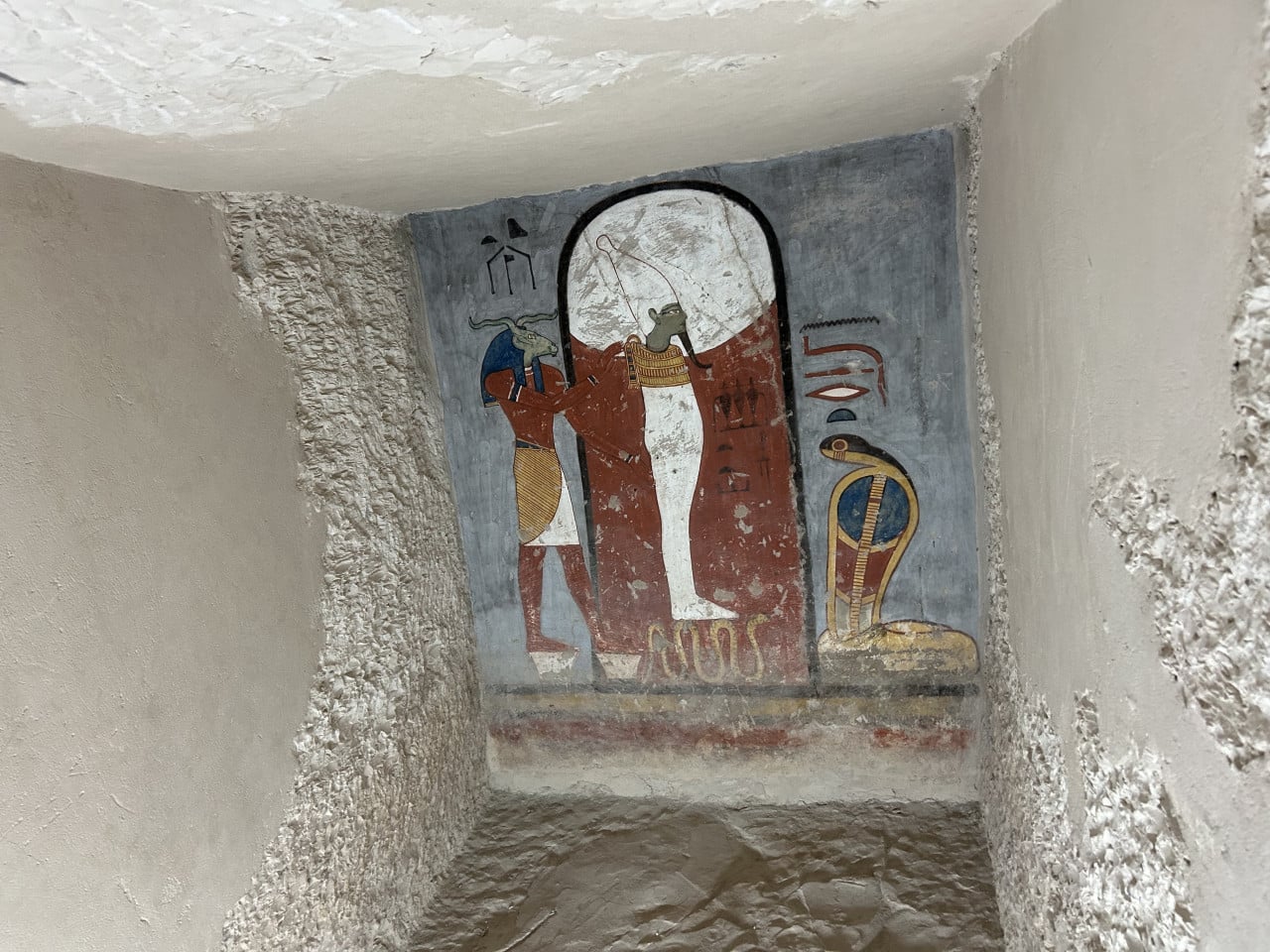 Nástěnná malba egyptských bohů v úzké skalní hrobce