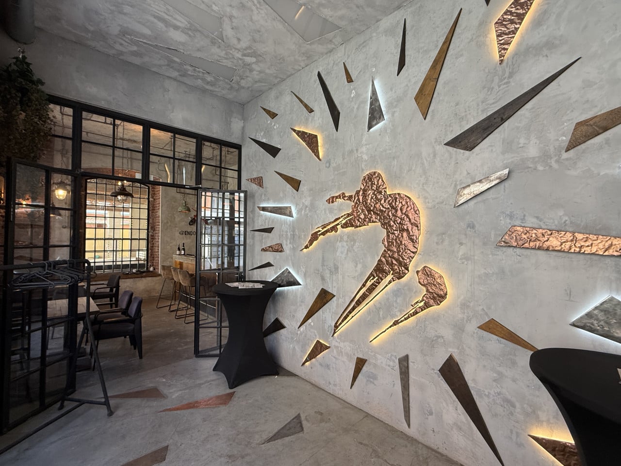 Stylový interiér únikové hry Saw s osvětleným Jigsawem na stěně v Praze