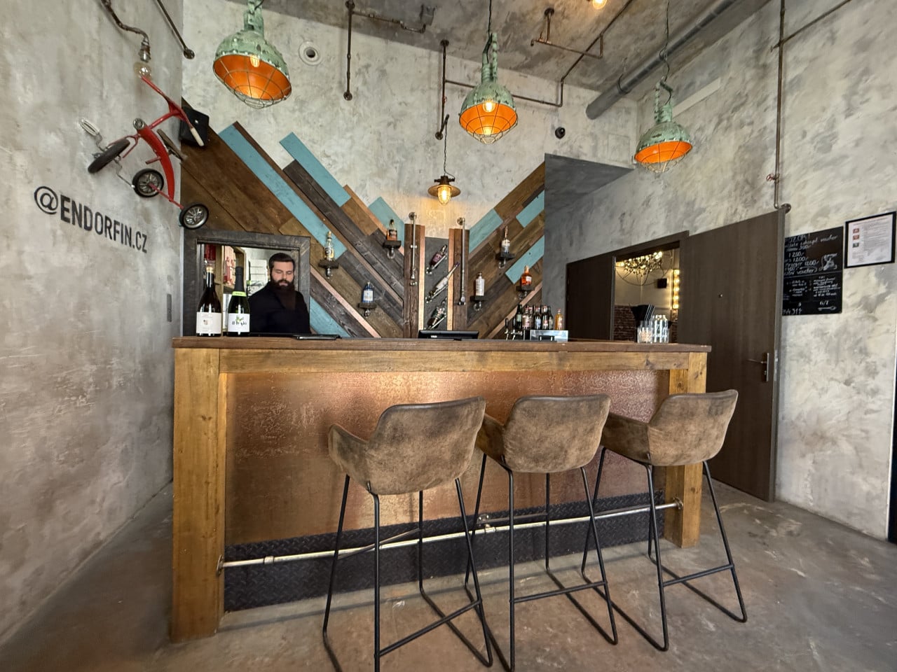 Recepce únikové hry Endorfin s barem, stoličkami a industriálním osvětlením.