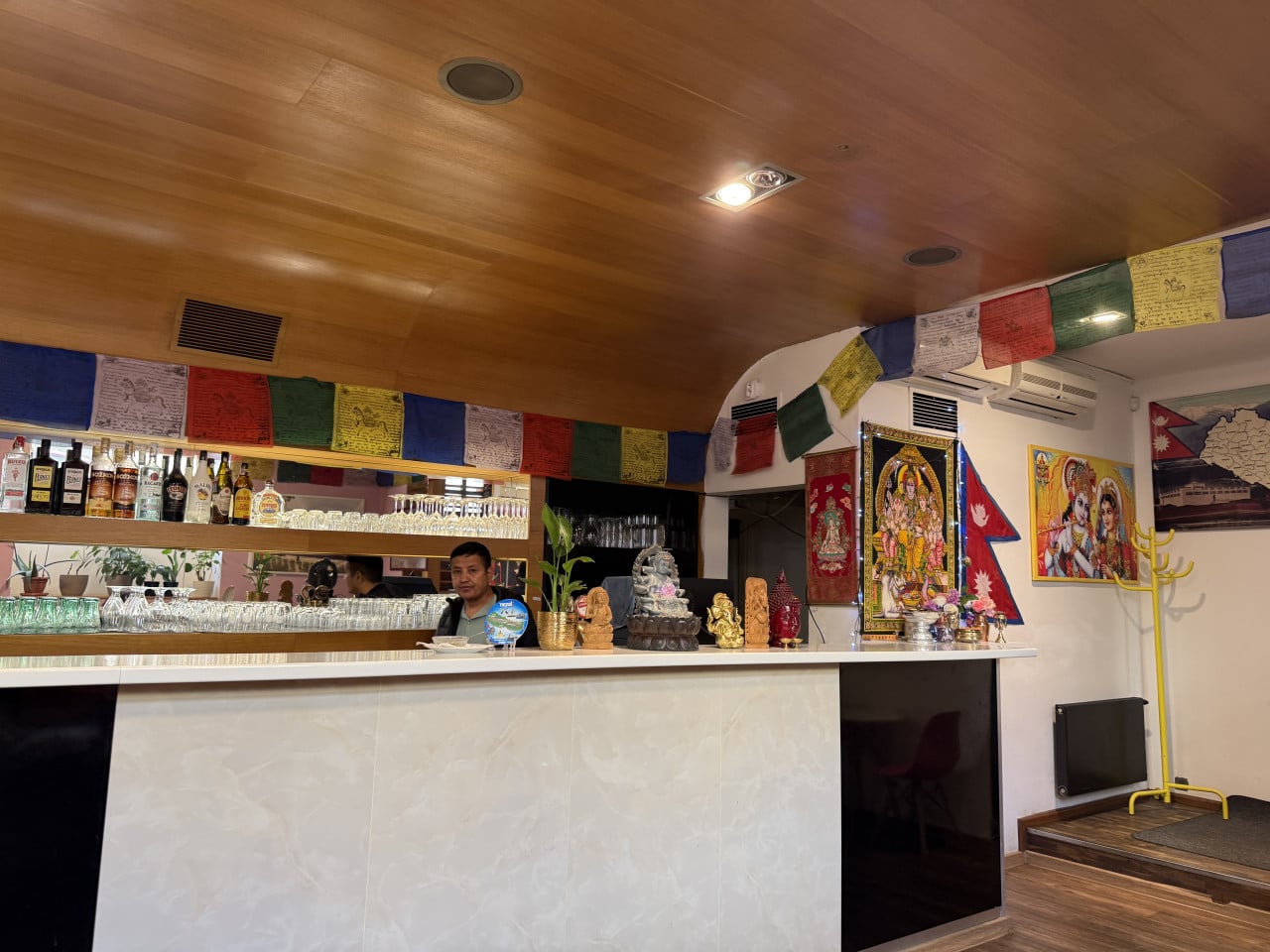 Bar s barem, náboženskými obrazy a modlitebními praporky v interiéru.