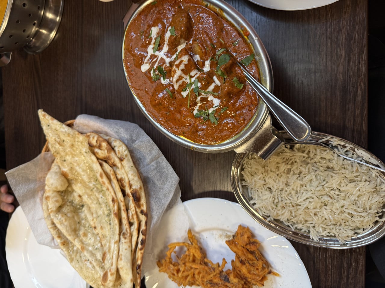 Indické jídlo s kari, rýží a naanem na stole