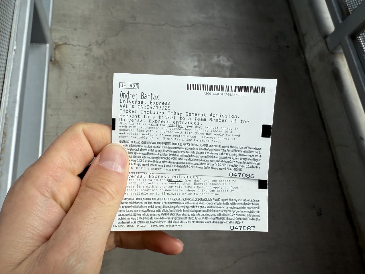 Ruka drží vstupenku Universal Express s čárovým kódem v průchodu.