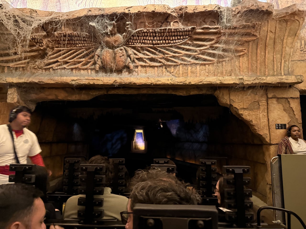 Před vstupem do jízdní atrakce s egyptským reliéfem a cestujícími v sedačkách