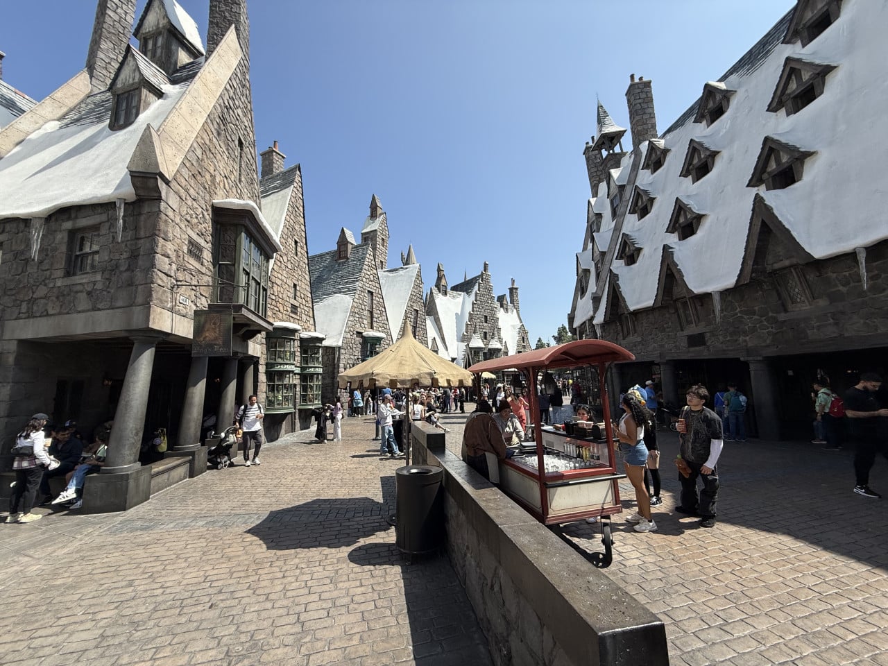 Průchod vesnicí Prasinek v Universal Studios s zasněženými střechami a turisty
