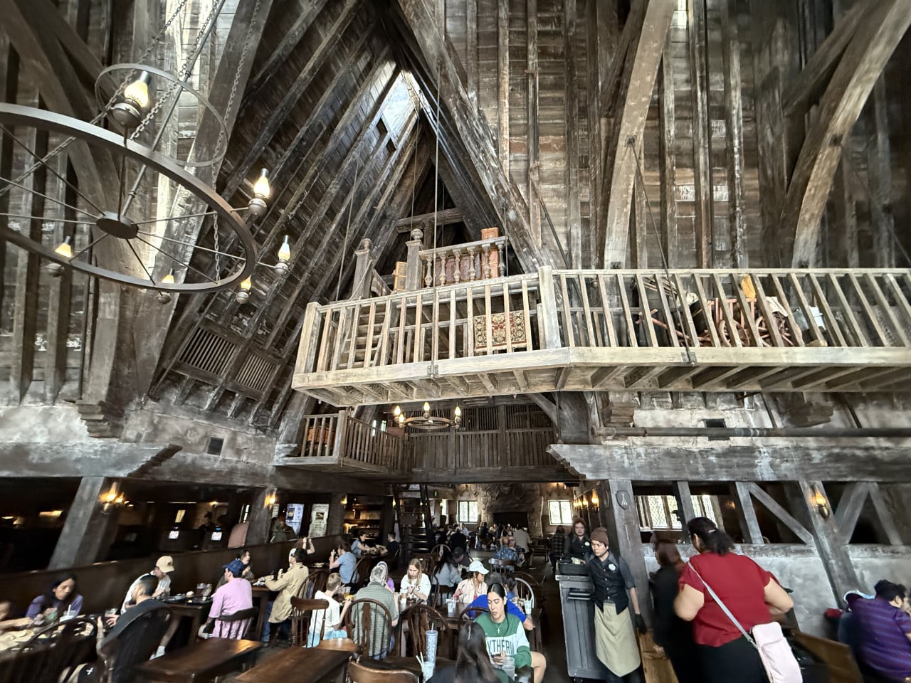 Rušná dřevěná jídelna v tematickém stylu s vysokým trámovým stropem a balkony