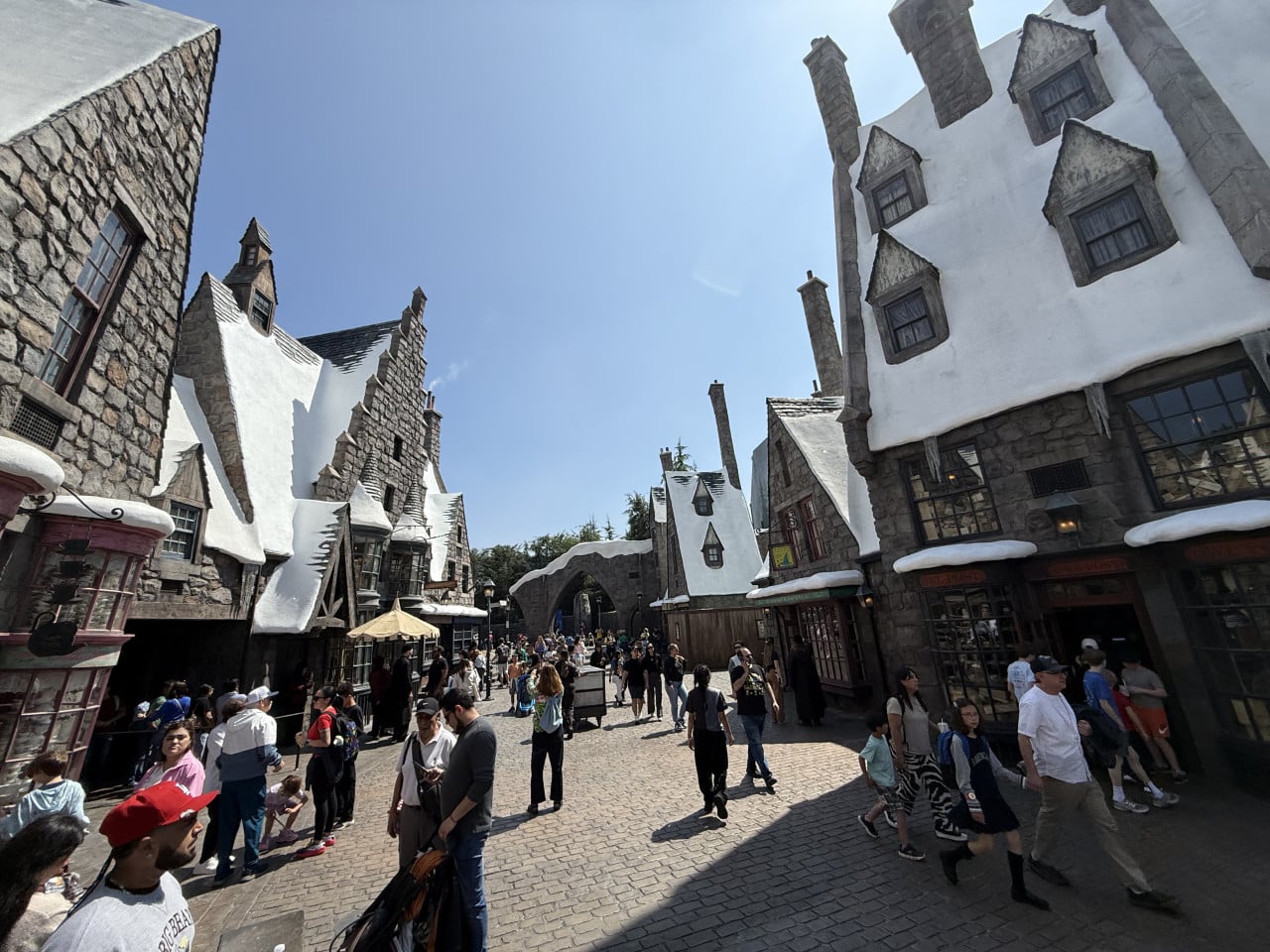 Návštěvníci procházejí zasněženou kouzelnickou vesnicí s kamennými domy v Universal Studios Hollywood