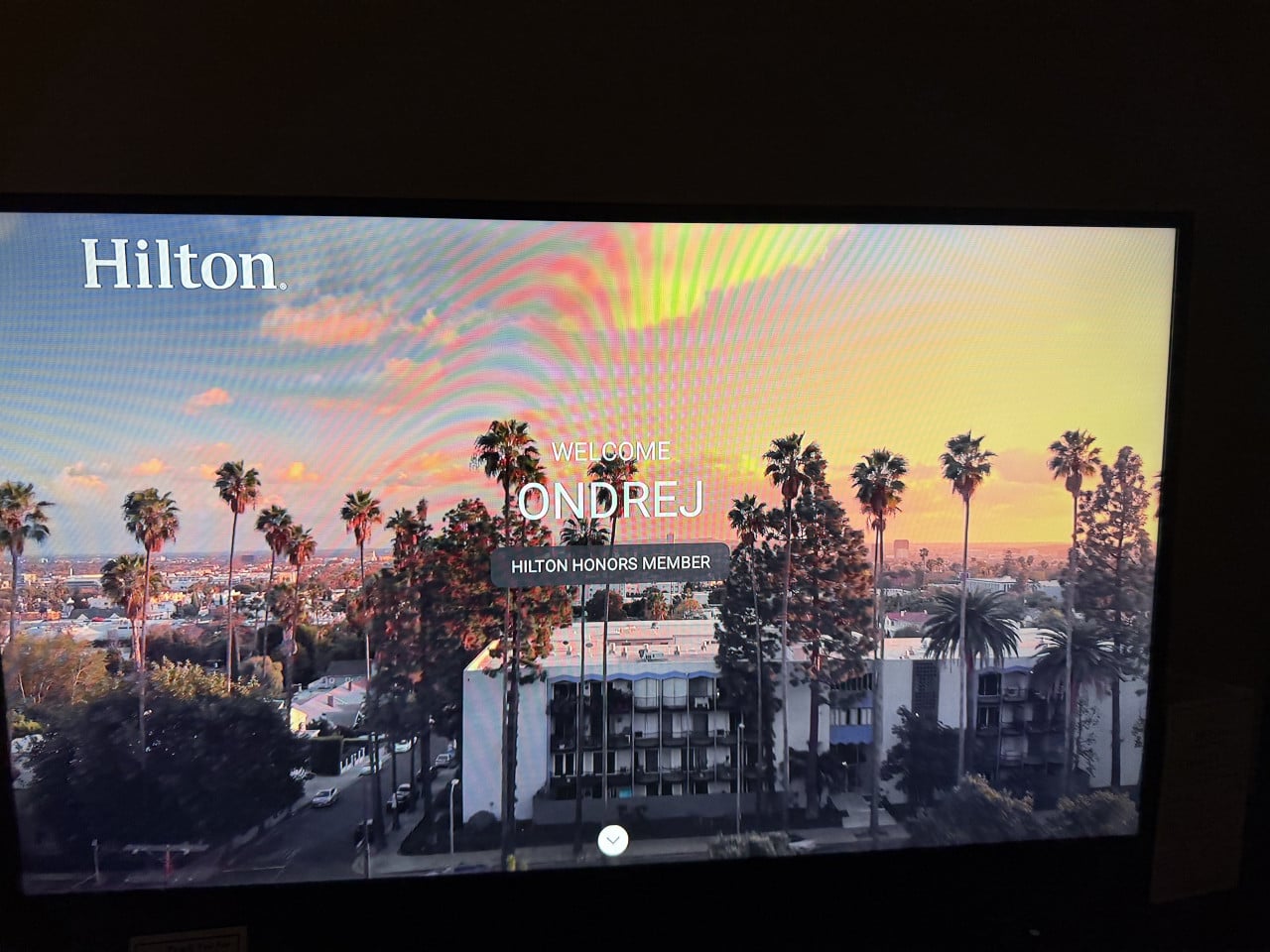 Hilton uvítací obrazovka s textem WELCOME ONDREJ a palmami při západu slunce