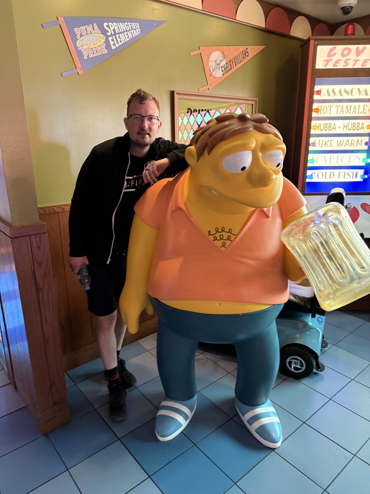 Muž stojí vedle sochy Barte Simpsona v obchodě s tematickými suvenýry.