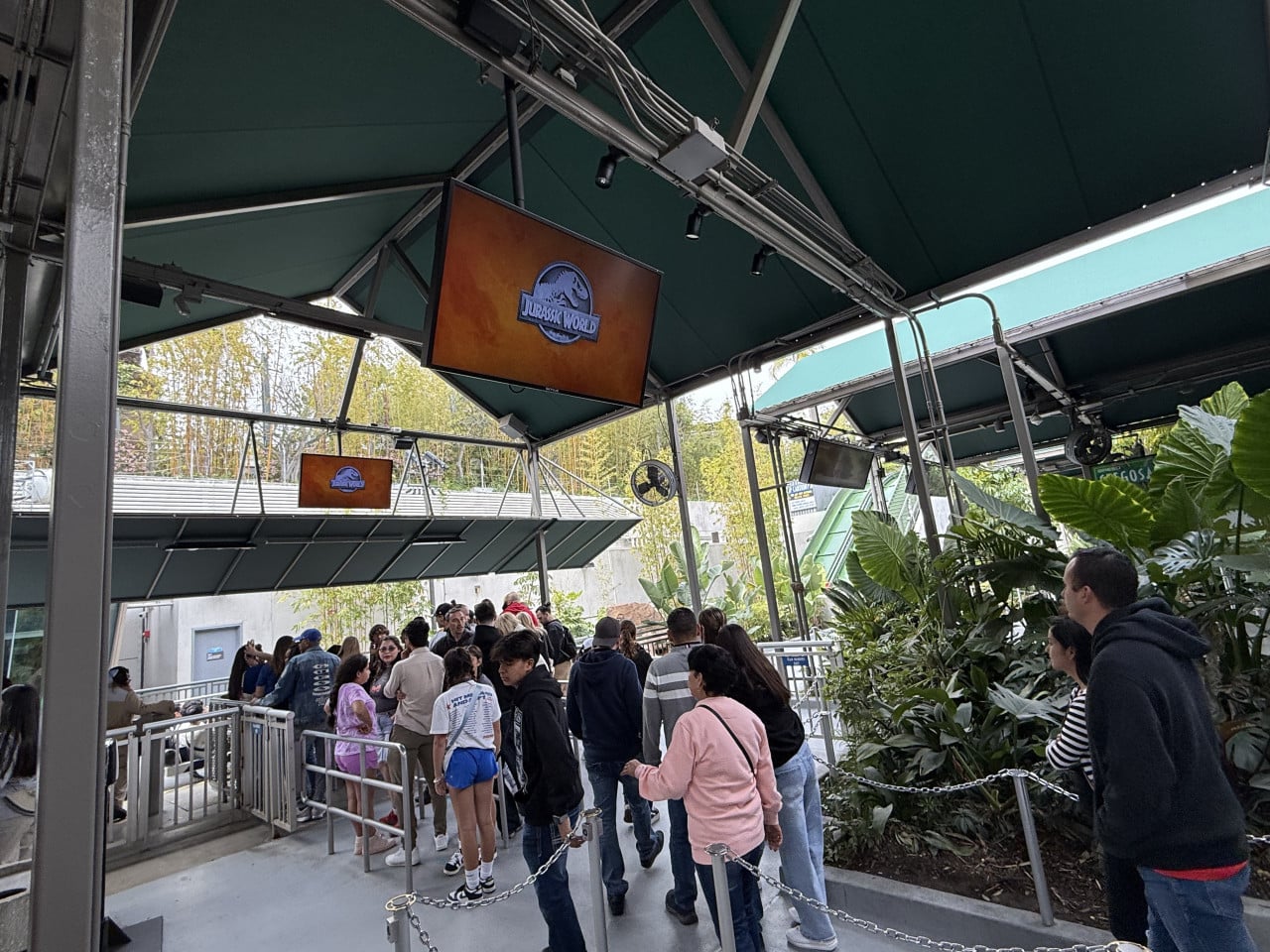 Fronta návštěvníků pod zeleným přístřeškem u Jurassic World atrakce v Universal Studios Hollywood