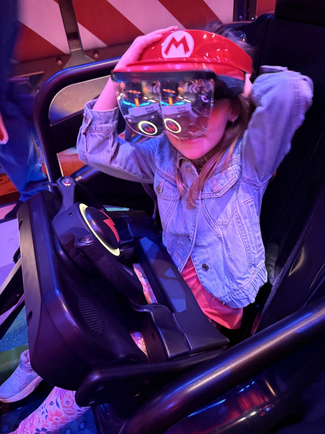 Dítě v sedadle atrakce s helmou Super Maria a ochrannými brýlemi, Universal Studios.