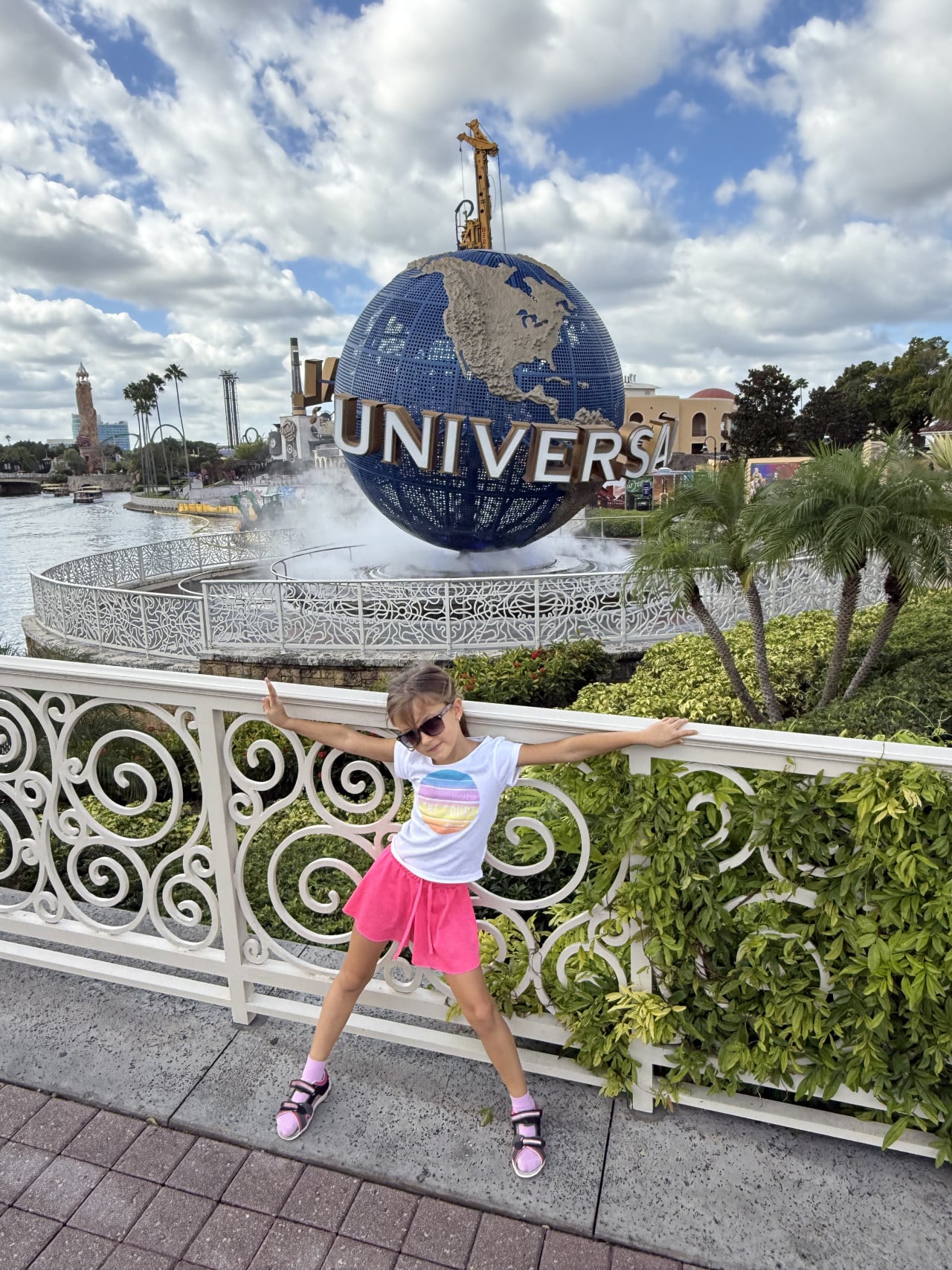 Dívka pózuje u fontány s glóbem Universal Studios Orlando pod zamračenou oblohou