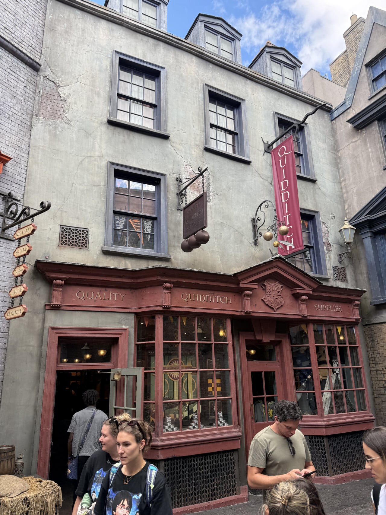 Obchod Quality Quidditch Supplies v kouzelnické uličce s návštěvníky před vchodem