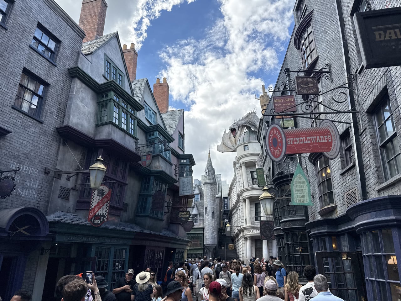 Hogsmeade Street s davy a drakem v Universal Studios Orlando, plno návštěvníků.