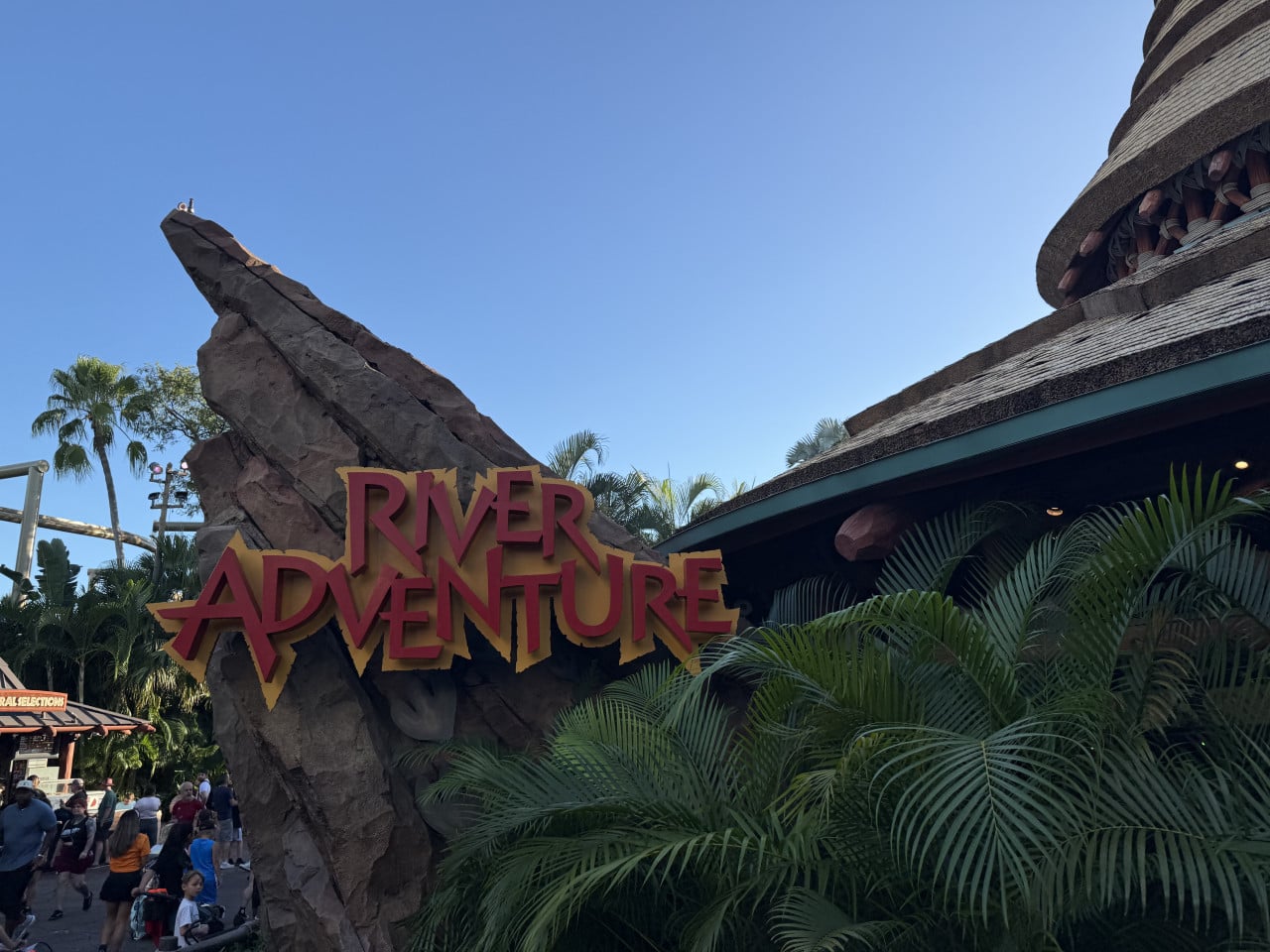 Vstup do atrakce River Adventure v Universal Studios Orlando s palmami a návštěvníky.
