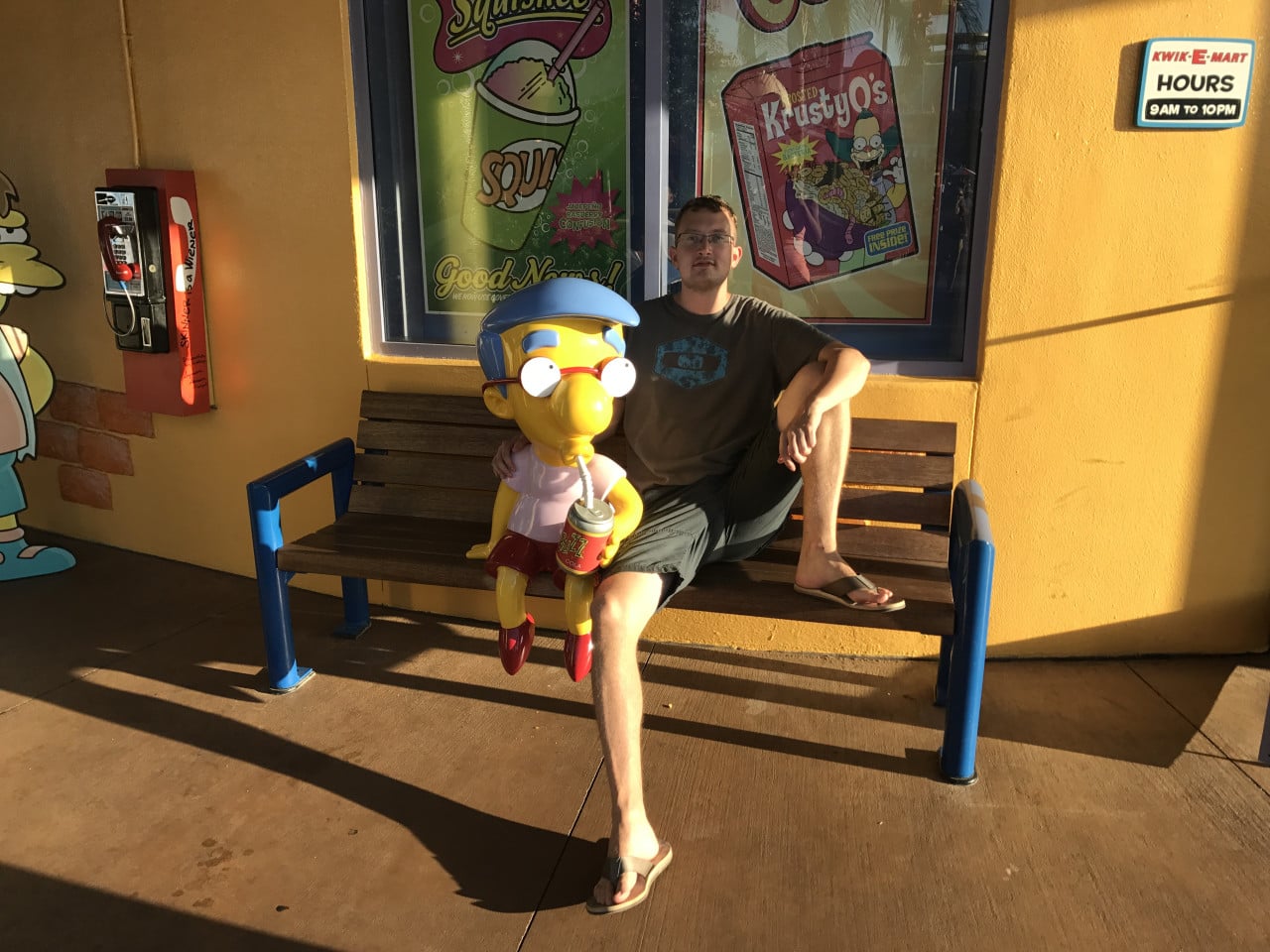 Muž sedí vedle sochy Barta Simpsona před obchodem Kwik-E-Mart v Universal Studios Orlando.