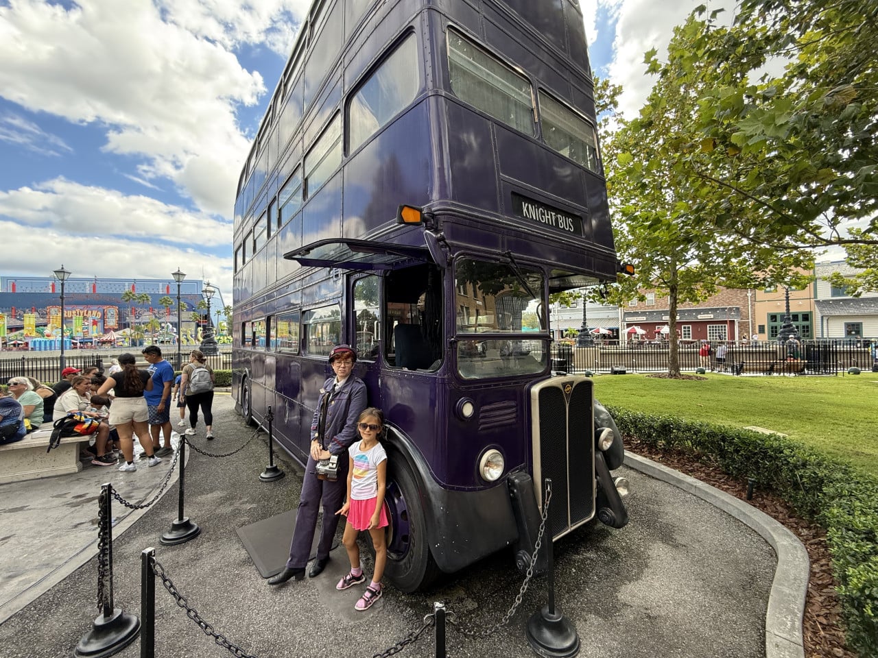 Dvojposchoďový fialový Knight Bus v Universal Studios Orlando s dívkou a průvodkyní.
