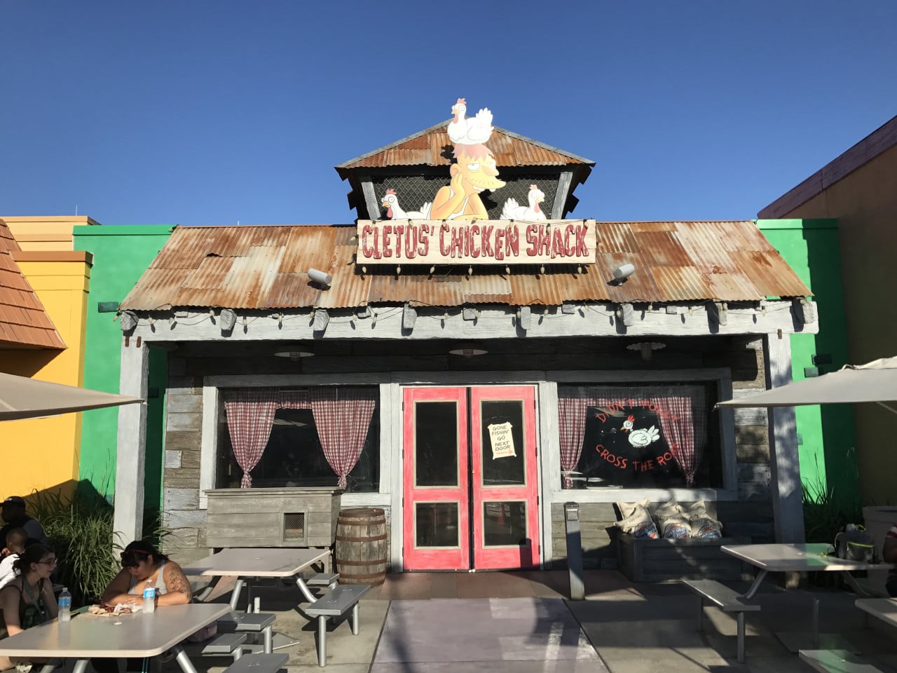 Průčelí restaurace Cletus’ Chicken Shack s popkulturním nápisem a venkovním posezením.