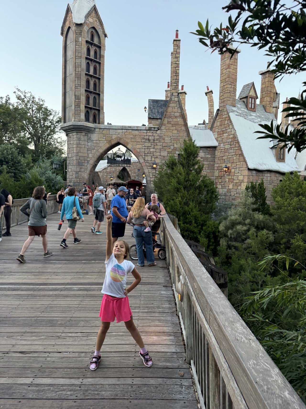 Dívka pózuje na dřevěném mostě před kamenným fantasy hradem v Universal Orlando.