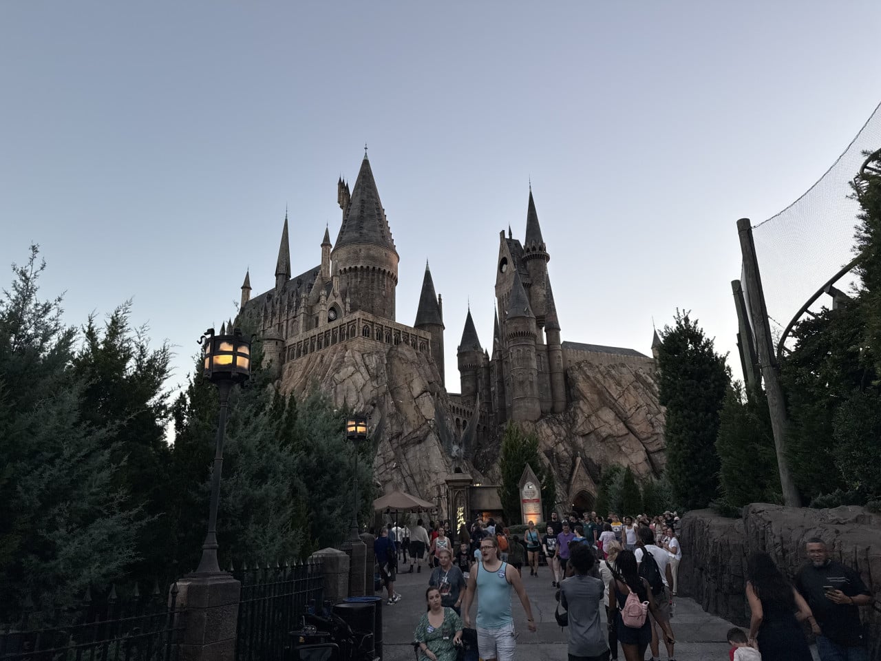 Hrad Bradavice v Universal Studios Orlando s návštěvníky na cestě a zapadajícím světlem