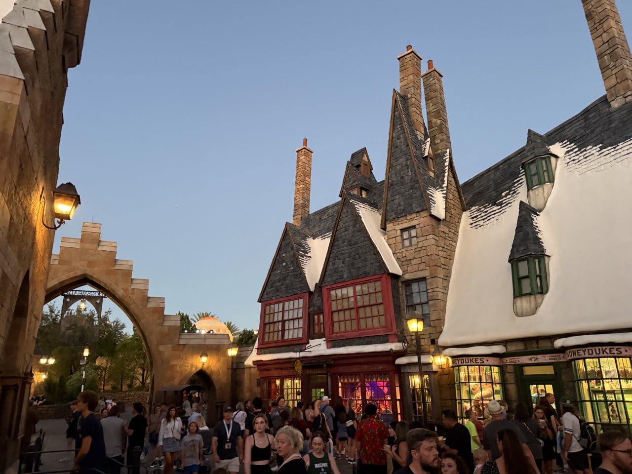 Pohled na kouzelnickou uličku s obchodem Honeydukes a davem návštěvníků v Universal Orlando
