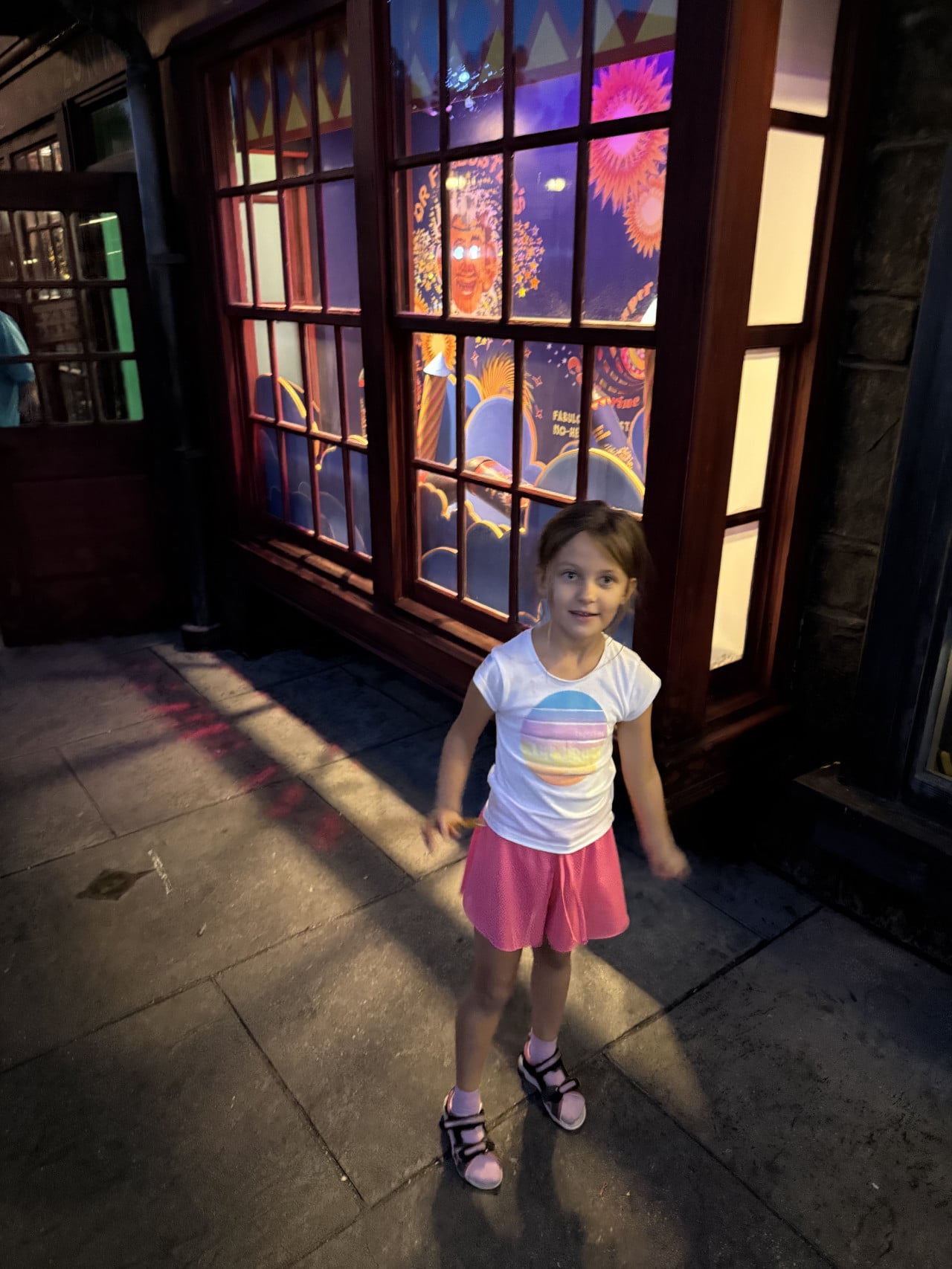 Malá dívka stojí před barevným dinoparkovým oknem v Universal Studios Orlando.