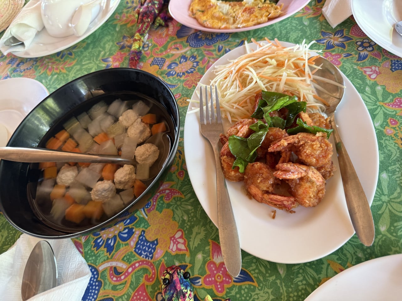 Miska čiré polévky s masovými kuličkami, vedle talíř smažených krevet a salátu