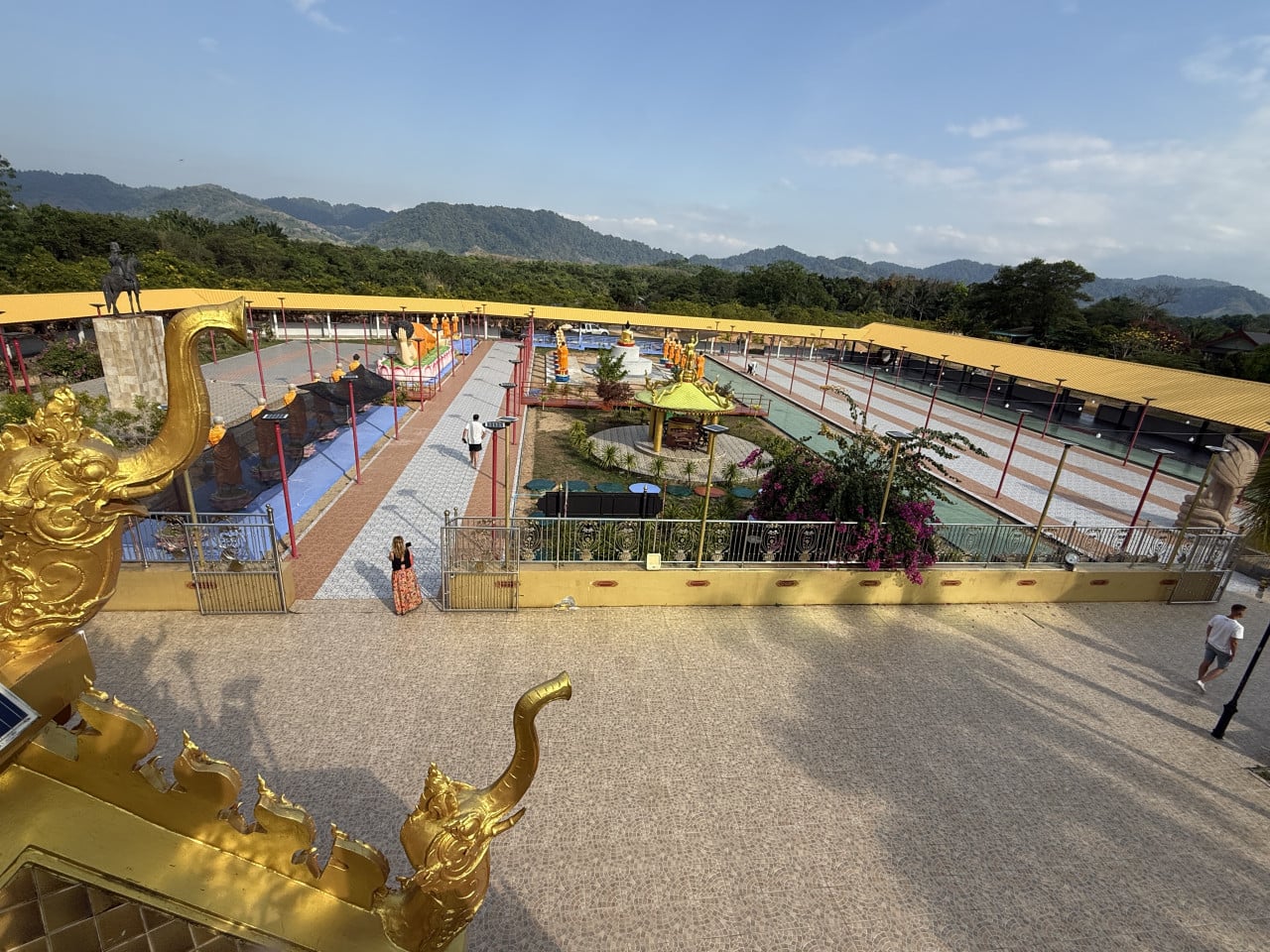 Nádvoří chrámu Wat Kongka Phimuk s pozlacenými hady, budovami a horami