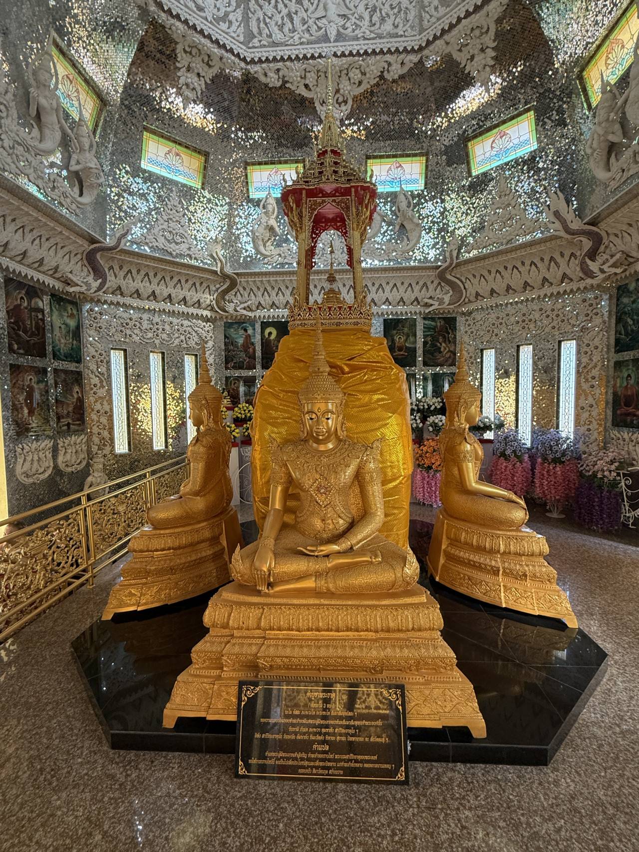 Zlatý Buddha a dvě boční sochy v zrcadlové svatyni, tabulka s thajštinou.