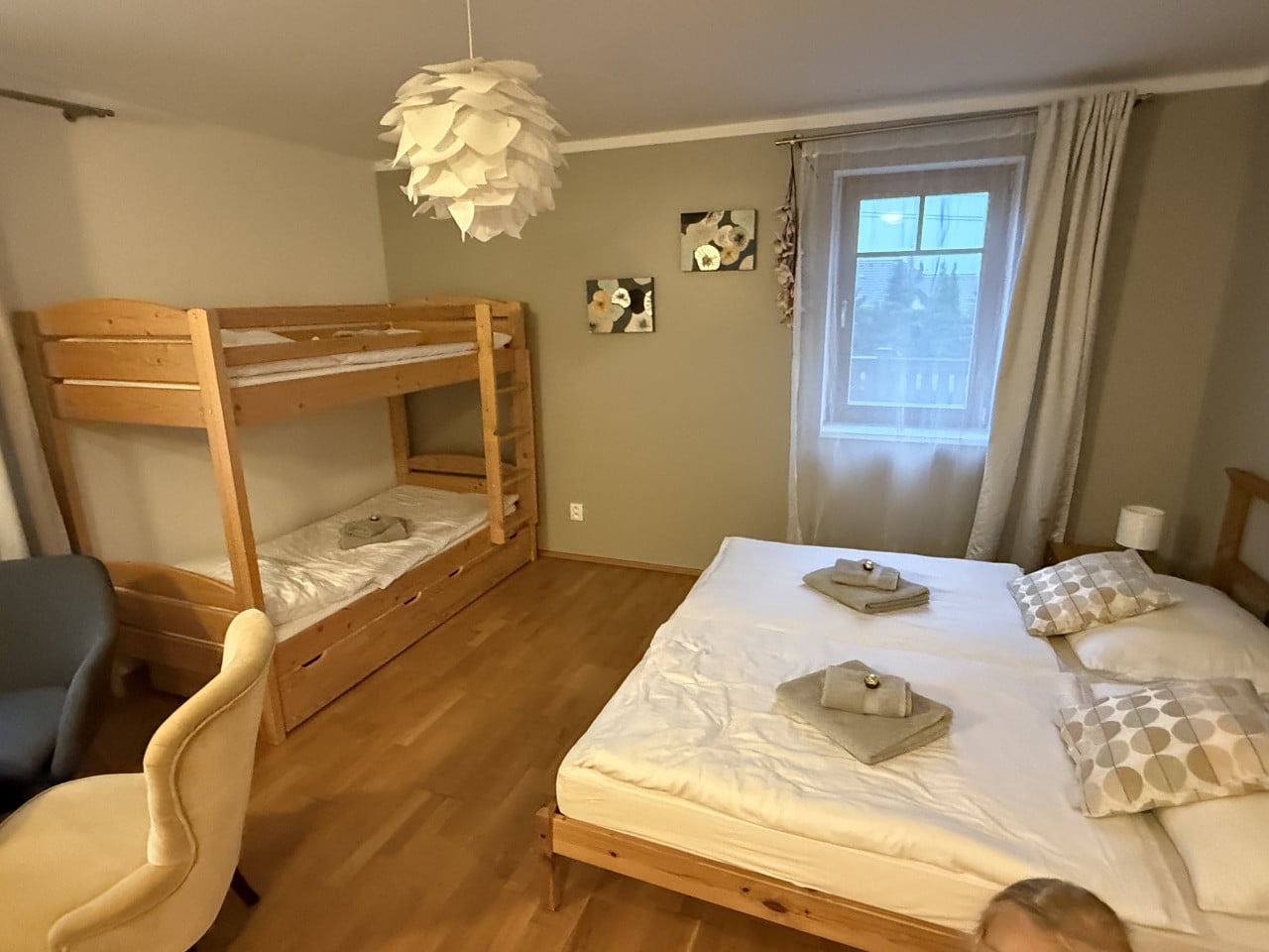 Útulná ložnice s manželskou postelí, palandou, oknem a dřevěnou podlahou.